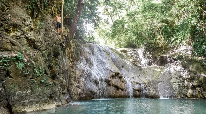 Ingkumhan Falls dropping beside a mossy cliff into a clear pool