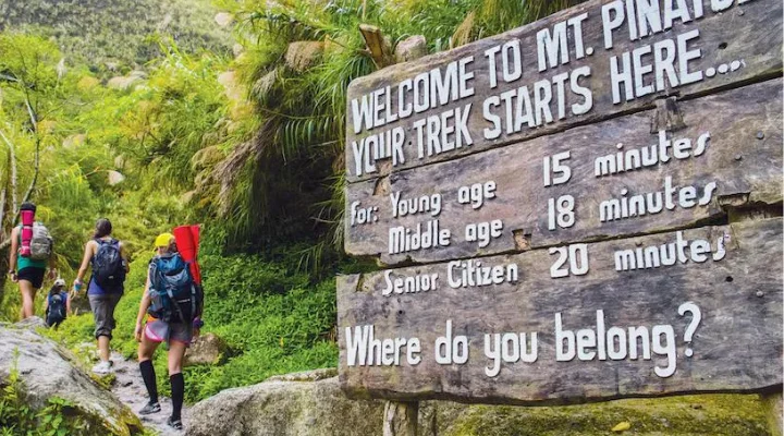 Trekkers at the Mount Pinatubo welcome sign showing trail times