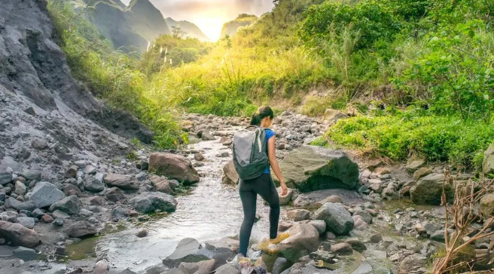 Hiker crossing a rocky stream on the Mount Pinatubo trail