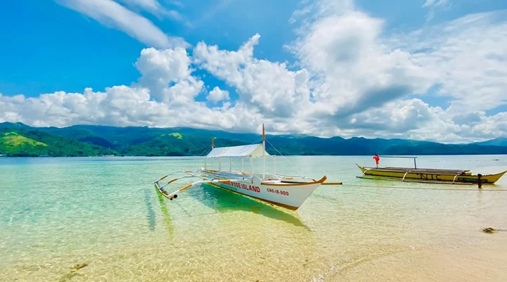 Outrigger boats in the shallow turquoise water at Aguirangan Island